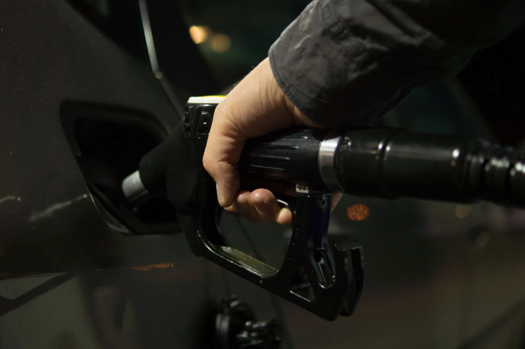 Persona llenando el tanque de combustible de un vehículo en una estación de servicio