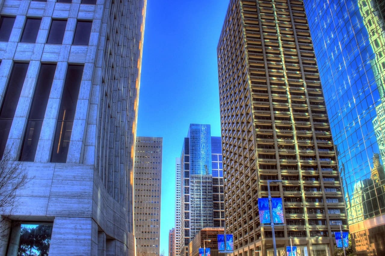 A modern cityscape at dusk with a busy highway in the foreground